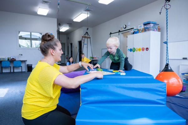 bright-clinical-space-playroom-pediatric-therapy-woman-therapist-toddler-patient-solving-puzzle-roseburg-oregon-explore-engage-enjoy-pediatric-therapy