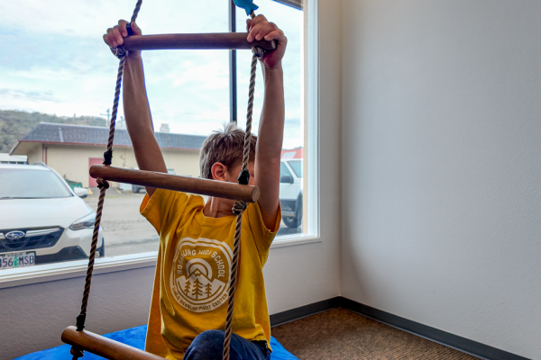 boy-in-yellow-shirt-and-jeans-climbing-indoors-for-physical-therapy-in-childrens-clinic-safe-environment