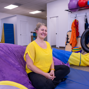 rebecca-moyer-pediatric-occupational-therapy-sitting-cross-legged-on-floor-of-explore-engage-enjoy-colorful-playroom-oregon rebecca-moyer-pediatric-occupational-therapy-sitting-cross-legged-on-floor-of-explore-engage-enjoy-colorful-playroom-oregon
